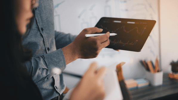 Two agency employees look at a colorful graph on a tablet.